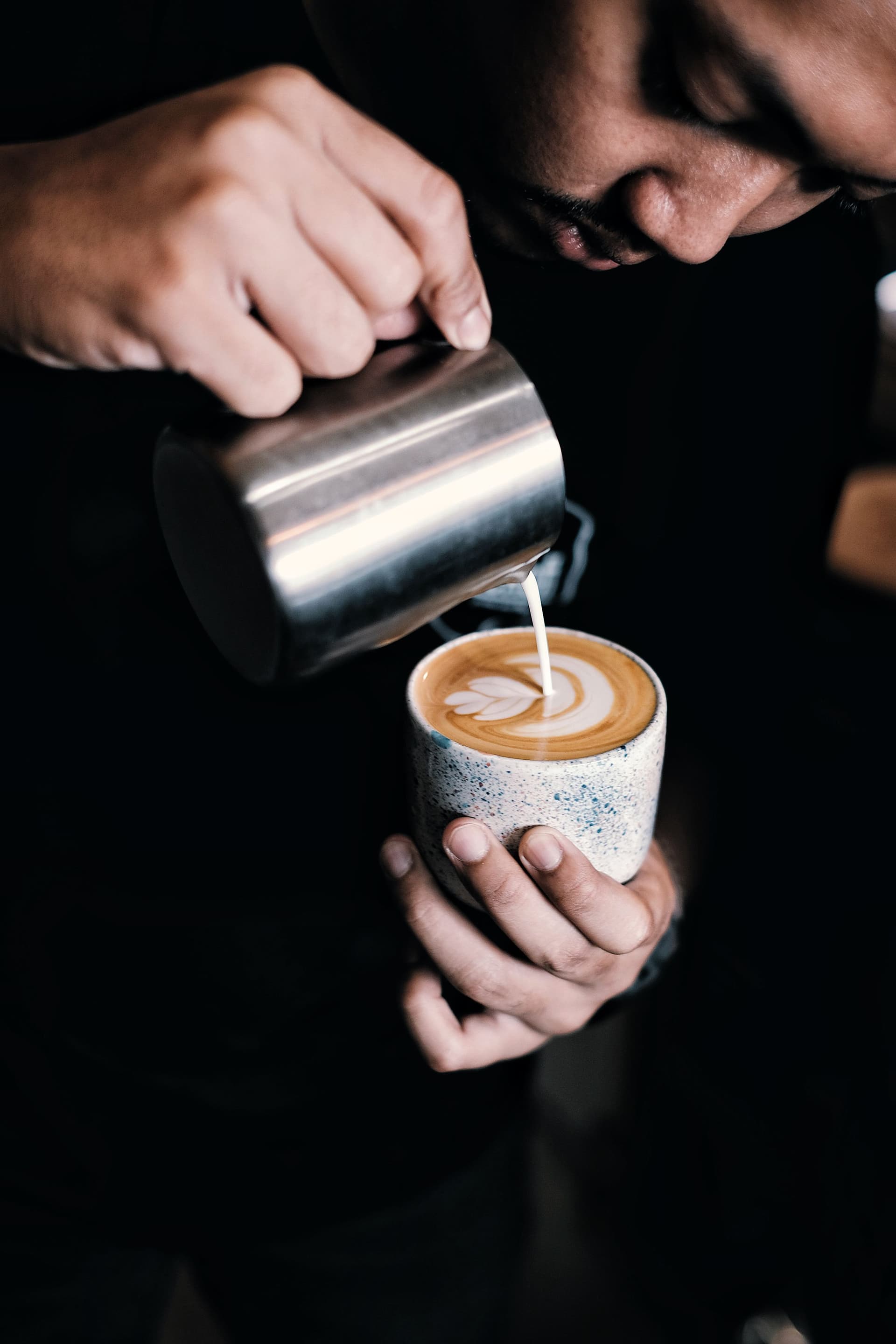 A barista pouring latte art at a fully branded Aroma Baristas coffee bar